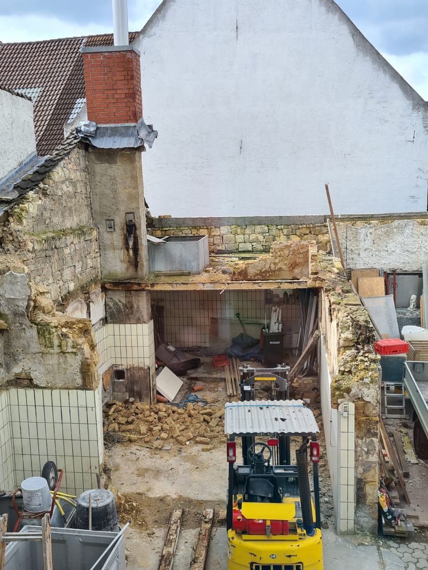 Teilweise rückgebautes Gebäude mit freigelegtem Bruchsteinmauerwerk, gefliesten Innenwänden und Bauschutt im Erdgeschoss